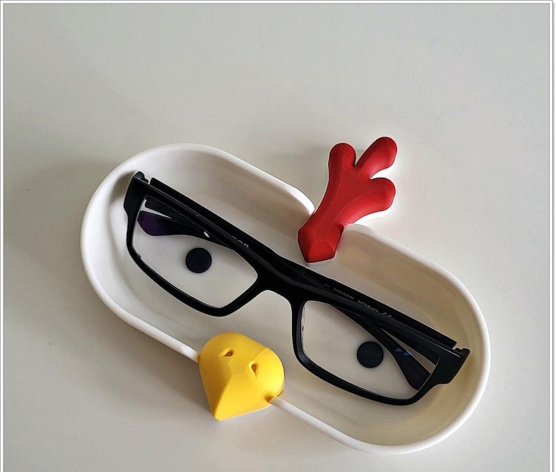 May include: White ceramic glasses holder shaped like a chicken with a red comb, yellow beak, and black glasses resting inside.