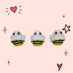 May include: Three small white and yellow bee-themed eraser toppers with cute cartoon faces.