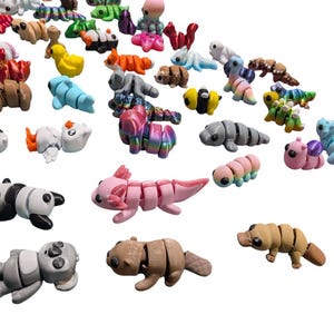 Peut inclure: Une collection de figurines d'animaux segment&eacute;s color&eacute;s, dont des pandas, des axolotls et des chenilles. Les figurines sont de diff&eacute;rentes couleurs, comme le rose, le marron et le bleu, et sont dispos&eacute;es sur un fond blanc. Ces jouets conviennent aux enfants.