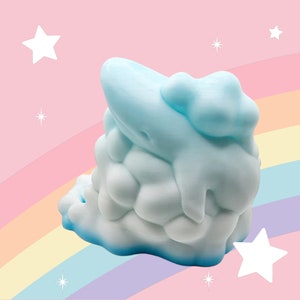 Puede incluir: Objeto en forma de nube azul claro con superficie texturizada. La nube tiene una base azul oscuro y detalles goteantes. El fondo presenta un arco&iacute;ris y estrellas, creando un tema caprichoso.