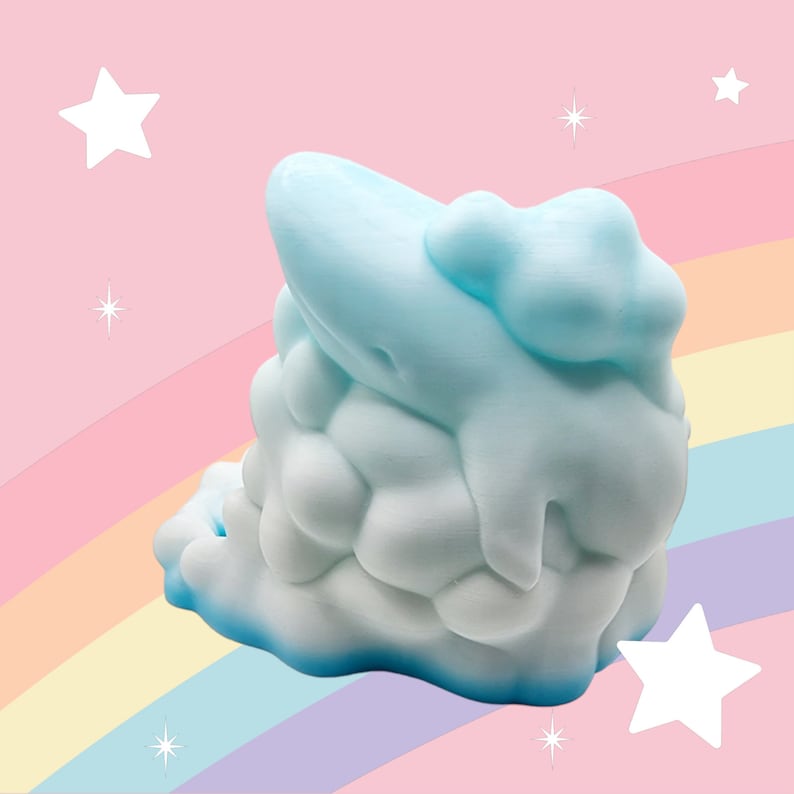 Puede incluir: Objeto en forma de nube azul claro con superficie texturizada. La nube tiene una base azul oscuro y detalles goteantes. El fondo presenta un arco&iacute;ris y estrellas, creando un tema caprichoso.