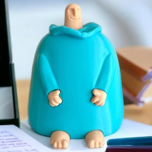 May include: A 3D printed figurine of a person wearing a blue robe. The figurine has a rounded body and a simple face with a smile.