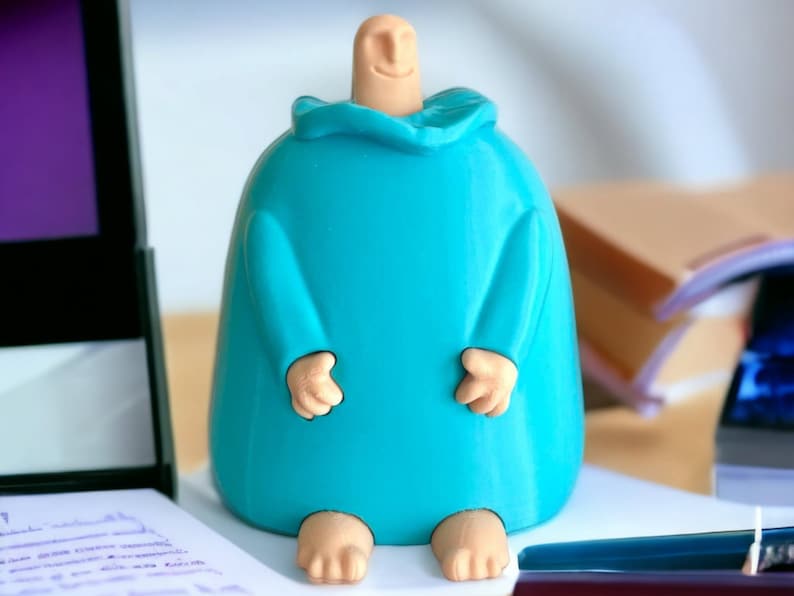 May include: A 3D printed figurine of a person wearing a blue robe. The figurine has a rounded body and a simple face with a smile.