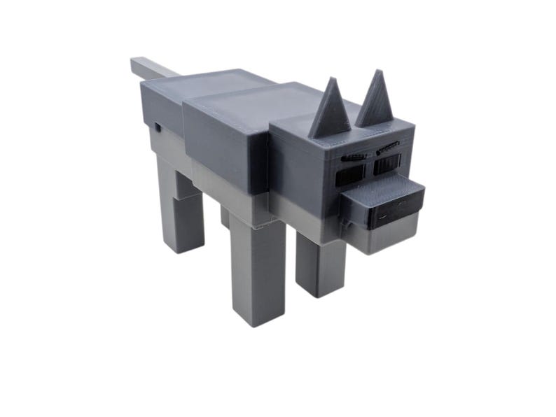 May include: A grey and light grey blocky wolf figurine. The wolf has a rectangular body, legs, and head, with triangular ears and a small tail. The eyes and nose are black. The figurine is likely 3D-printed.