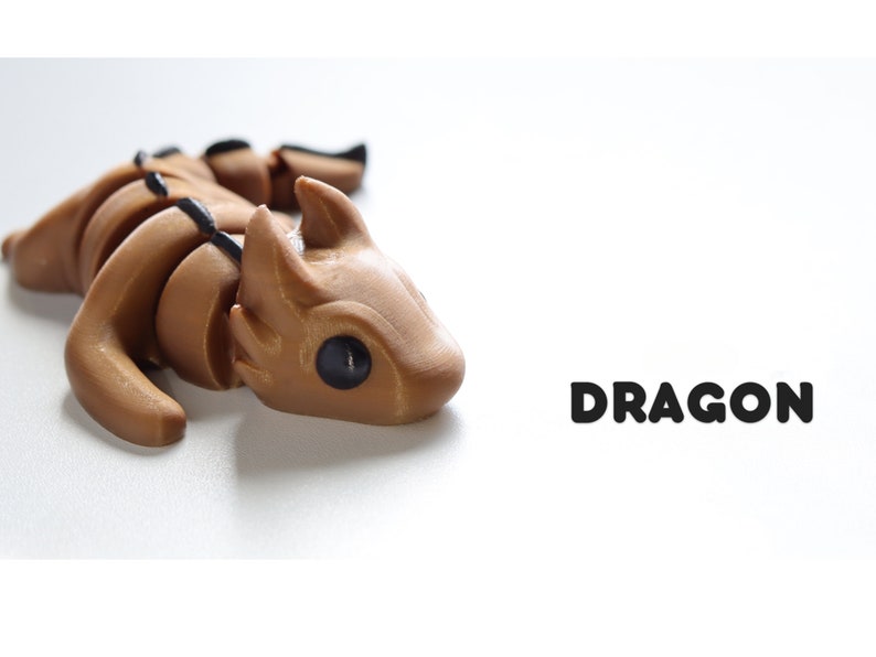 May include: A brown, articulated dragon figurine with black eyes. The figurine is lying on its side with its head turned to the right. The word "DRAGON" is printed in black letters on a white background.