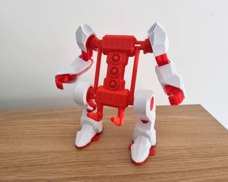May include: A red and white articulated robot toy with wheels. The robot has a large red body with four white wheels and a red frame. The robot's arms and legs are articulated and can be moved into different positions.