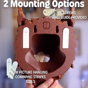 May include: A brown decorative wall hanging with a textured surface. The image shows two mounting options: screws and 3M picture hanging command strips. Text on the image reads "2 Mounting Options", "3M Picture Hanging Command Strips", and "Size S".