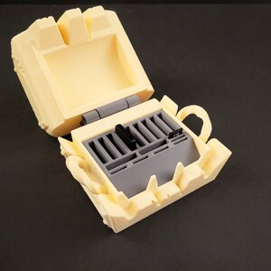 May include: A yellow plastic case with a hinged lid, open to reveal a gray plastic storage compartment with slots for holding memory cards.