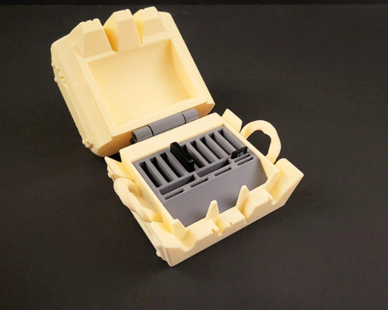 May include: A yellow plastic case with a hinged lid, open to reveal a gray plastic storage compartment with slots for holding memory cards.