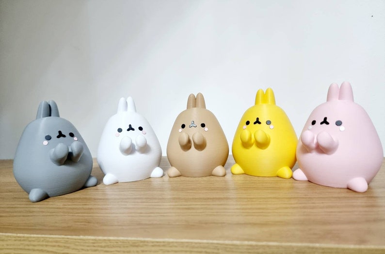 K&ouml;nnte beinhalten: F&uuml;nf kleine Pl&uuml;sch-Hasenfiguren in verschiedenen Farben: Grau, Wei&szlig;, Braun, Gelb und Rosa. Jeder Hase hat einen runden K&ouml;rper, kurze Beine und einen s&uuml;&szlig;en Ausdruck mit geschlossenen Augen und kleinen, erhobenen Armen.