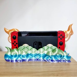 May include: A 3D printed stand for a Nintendo Switch console, featuring a colorful cloud design with gold accents. The stand has two horns on either side, resembling a mythical creature.