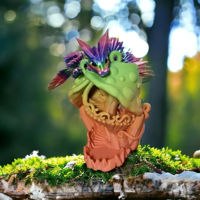 May include: A colorful, 3D printed dragon figurine with a green, textured head and a pink, purple, and blue body. The dragon is perched on a mossy log.