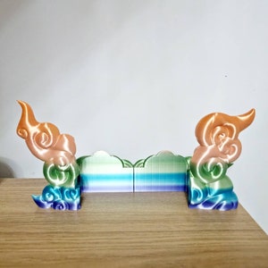 May include: A 3D printed decorative object with a rainbow gradient design. The object is shaped like a cloud with a swirling pattern. It is made of plastic and has a smooth finish.