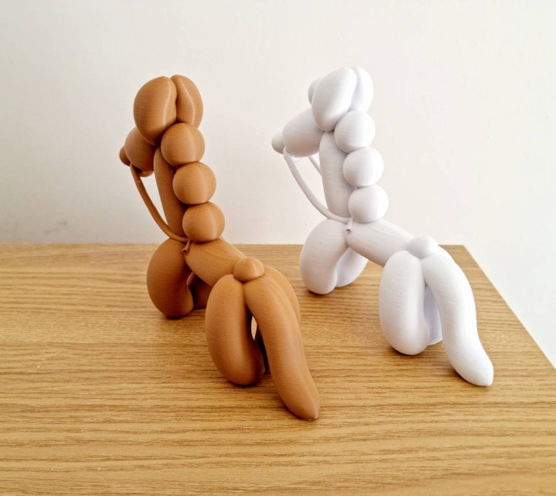 May include: Two balloon animal sculptures, one brown and one white, in the shape of a horse. The sculptures are made of a smooth, rubber-like material and have a realistic appearance.