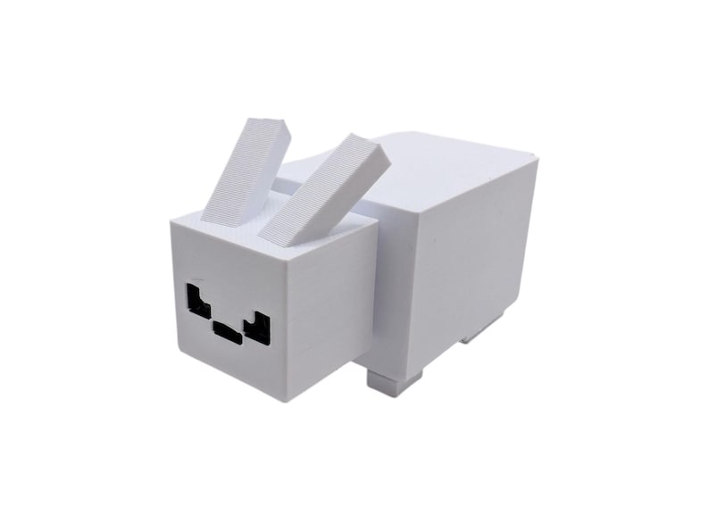 May include: A white, geometric rabbit sculpture with upright ears and black facial details. The rabbit is made from blocky shapes, giving it a pixelated look. The design is reminiscent of a video game character.