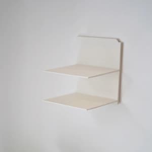 May include: A minimalist, white, two-tiered wall shelf. The shelf has a clean, modern design with two rectangular platforms. The shelf is mounted on a white wall, creating a simple and functional storage solution.