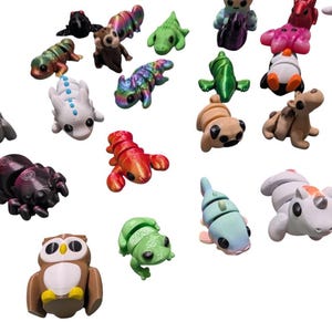 Peut inclure: Une collection de petites figurines d'animaux color&eacute;es, dont une araign&eacute;e, un hibou, une grenouille et un homard. Les figurines sont de diff&eacute;rentes couleurs, comme le marron, le vert et le rouge. La collection comprend une vari&eacute;t&eacute; de cr&eacute;atures.