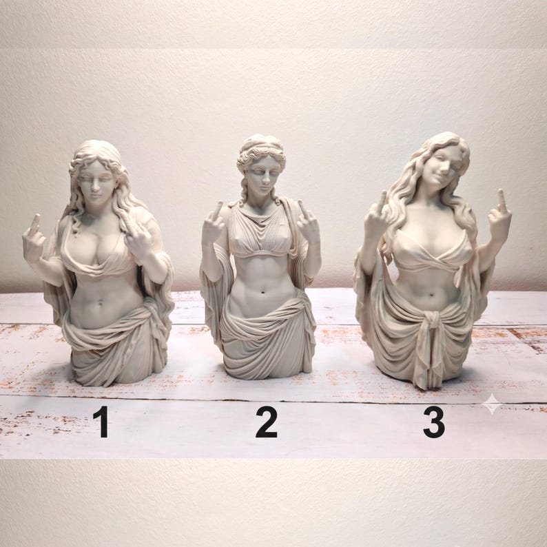 May include: Three off-white statues of female figures in classical drapery, each displaying a middle finger gesture. The figures are numbered 1, 2, and 3 at the base. Each bust features detailed hair and fabric folds, presented in a uniform matte finish.