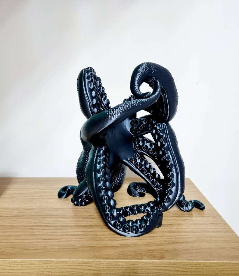 May include: A black octopus sculpture with detailed tentacles, made with a 3D printer. The octopus is curled up in a compact shape, with its tentacles intertwined.