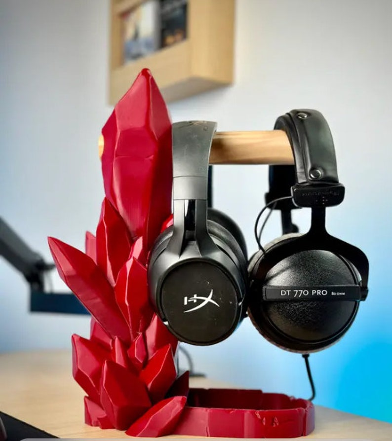 May include: A red crystal-shaped headphone stand with two pairs of headphones. One pair is black with the text "DT 770 PRO" and the other pair is black with a white logo.