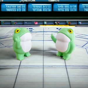 May include: Two green frog figurines with white bellies stand on a gridded surface. The frogs are facing each other and appear to be talking.