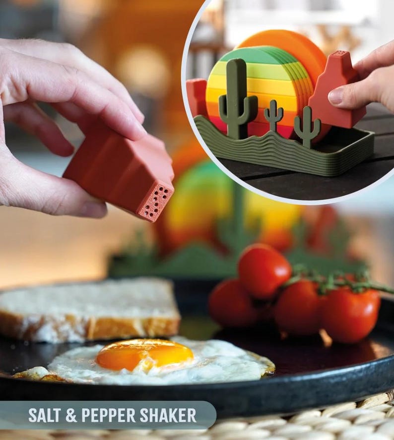May include: A terracotta-colored salt and pepper shaker set with a desert landscape design. The set includes a salt shaker, pepper shaker, and a holder with cacti and a mesa. The text "SALT & PEPPER SHAKER" is at the bottom.