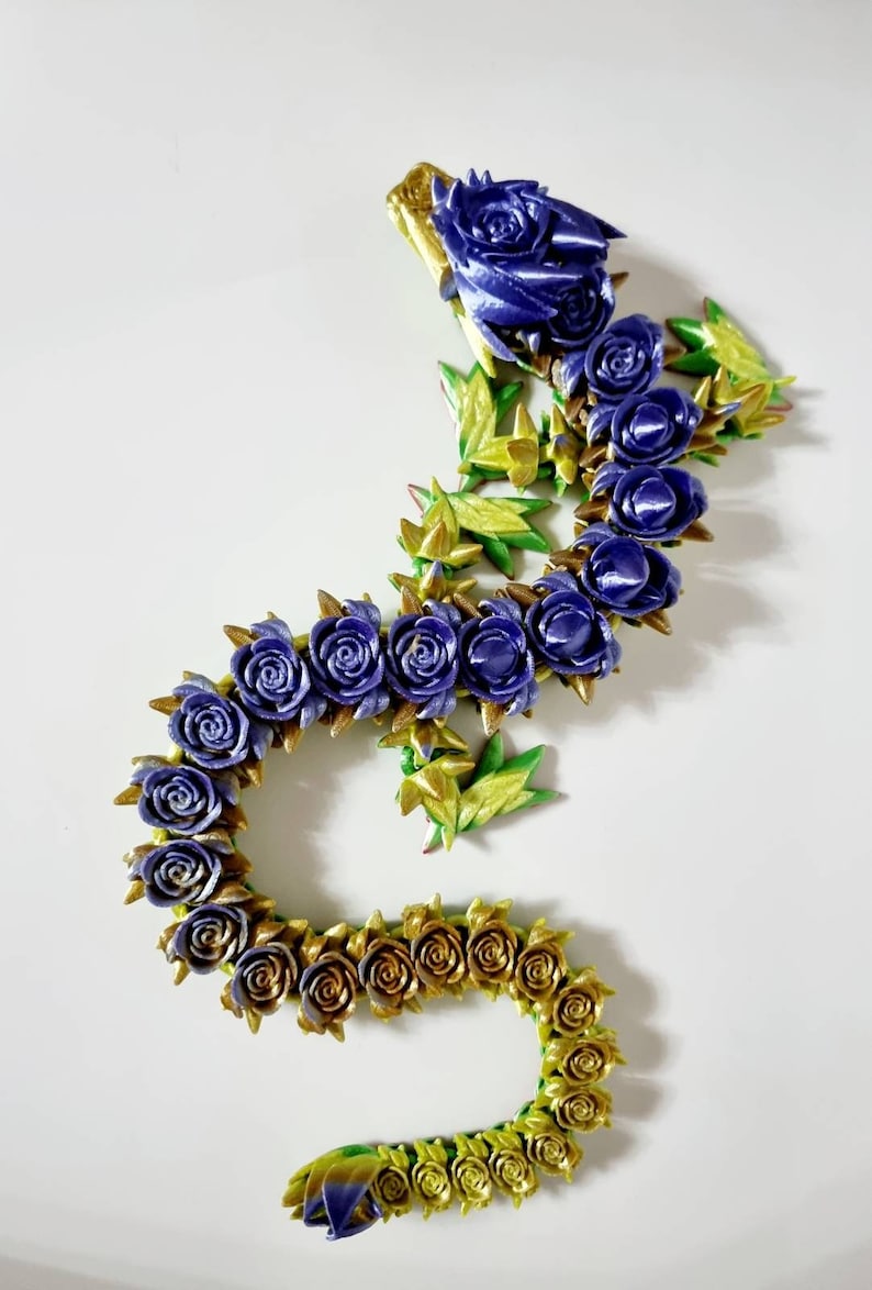 Peut inclure: Une guirlande florale violette et dor&eacute;e faite de roses et de feuilles en tissu. La guirlande est en forme de serpent ou de dragon.