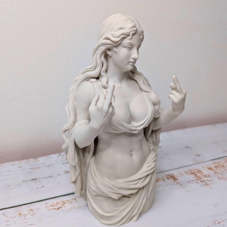 May include: A matte white sculpture of a figure with long flowing hair, wearing a draped garment that leaves the midriff exposed. The figure is depicted with both arms raised, extending the middle finger on each hand in a defiant gesture.