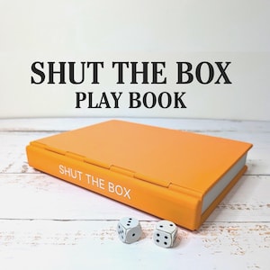 Juego de dados "Cierra la caja" – Juego de viaje con estilo de libro, decoración minimalista.