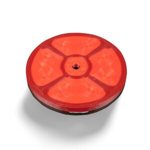 May include: A red, circular balance board with a textured surface. The board has a central hole and is divided into four sections by raised lines. The base is a darker color, creating a contrast. The product is designed for exercise and fitness.