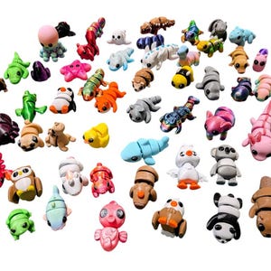 Peut inclure: Une collection de figurines miniatures color&eacute;es repr&eacute;sentant divers animaux et cr&eacute;atures. Les figurines pr&eacute;sentent une vari&eacute;t&eacute; de couleurs telles que le vert, le rose, le bleu et le marron. La collection comprend un poulpe, une grenouille et un panda.
