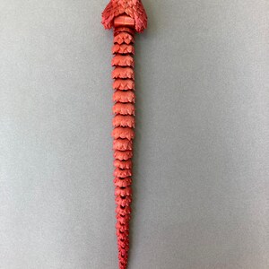 May include: A red snake made of plastic with a segmented body and a detailed head.