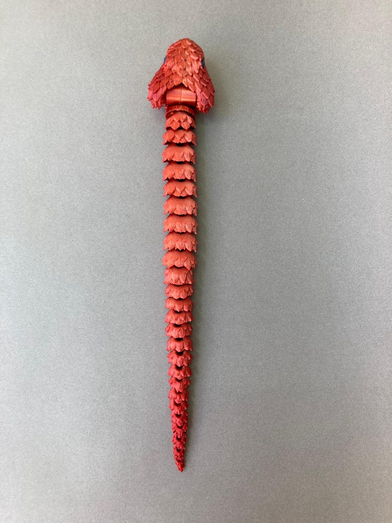 May include: A red snake made of plastic with a segmented body and a detailed head.