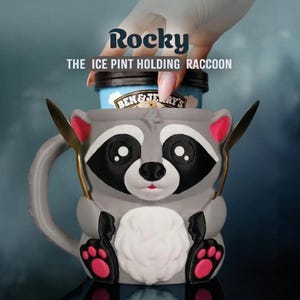 May include: A gray raccoon-shaped ice cream pint holder with the name "Rocky" and the text "THE ICE PINT HOLDING RACCOON". The holder has black and white facial features, pink accents, and holds a pint of ice cream.