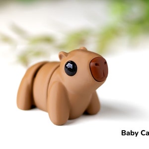 May include: A small, brown, toy capybara with black eyes and a brown nose. The toy is made of a smooth, rubbery material and has a cute, cartoonish appearance.