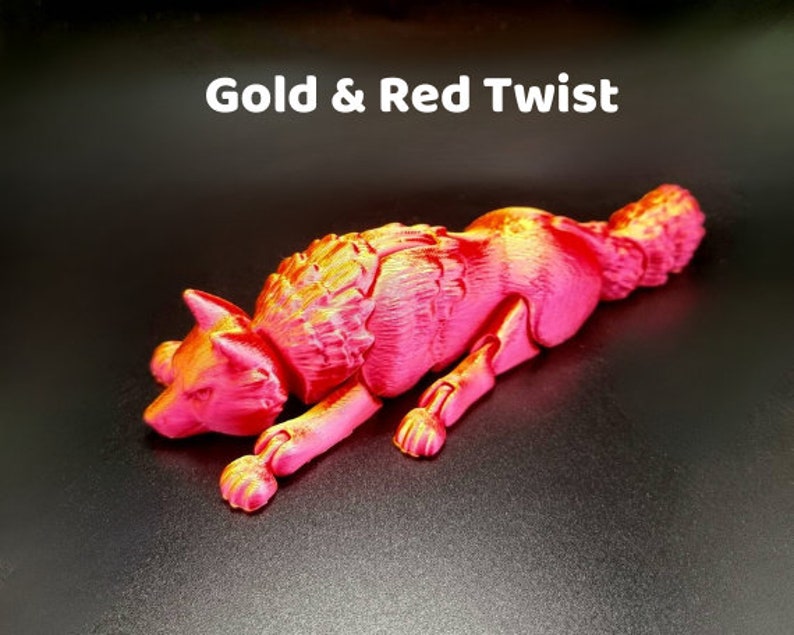 May include: A red and gold metallic wolf figurine with a textured fur design. The wolf is lying down with its head turned to the side. The figurine is made of plastic and is approximately 6 inches long.