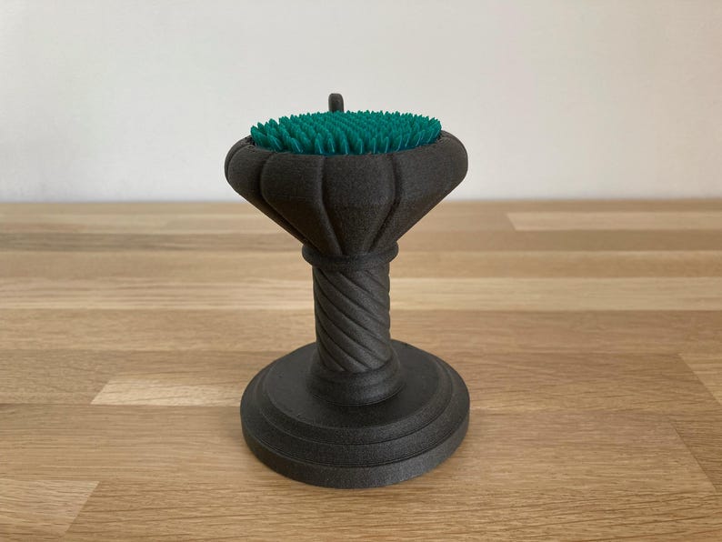 May include: A black, decorative pedestal with a green, textured top. The pedestal has a twisted column and a round base.