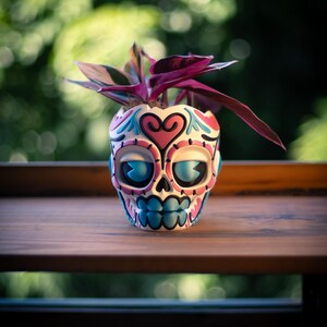 May include: A decorative skull-shaped planter with a colorful design, holding a plant with purple and green leaves. The planter features blue, pink, and white accents. The planter is sitting on a wooden surface.