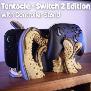 Puede incluir: Un soporte negro para consola y mando de Nintendo Switch con un diseño de tentáculos. El soporte es beige y marrón, y el texto "Tentacle - Switch 2 Edition with Controller Stand" es visible.