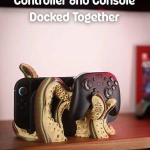 May include: A black game console and controller are docked together in a unique stand. The stand is designed with an octopus-like tentacle motif in tan and brown colors. The text "Controller and Console Docked Together" is displayed at the top.