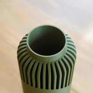 May include: A set of three ceramic mugs with a speckled, matte finish. The mugs are in shades of cream, light gray, and dark gray. Each mug has a simple, minimalist design and a rounded handle.