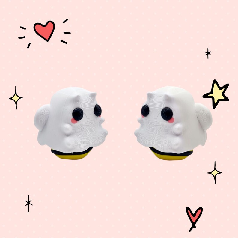 May include: Two white ghost-shaped figurines with black eyes and pink cheeks, each with a yellow and black bee-shaped base. The figurines are facing each other on a pink background.