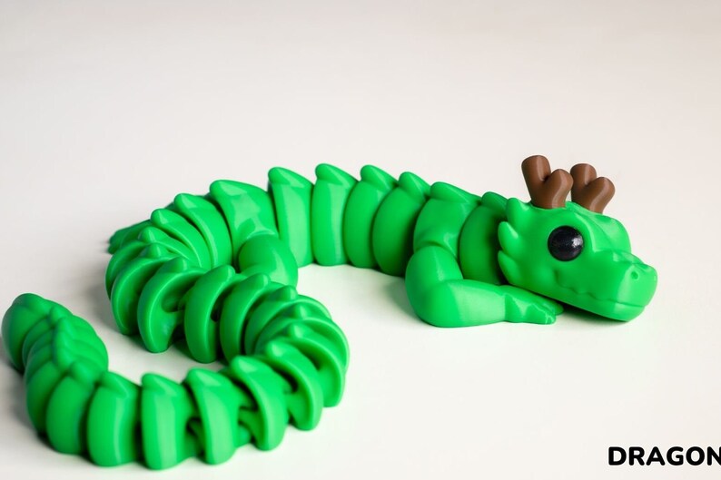 May include: A green segmented dragon figurine with brown antlers and large black eyes. The dragon is curled up in a sleeping position.
