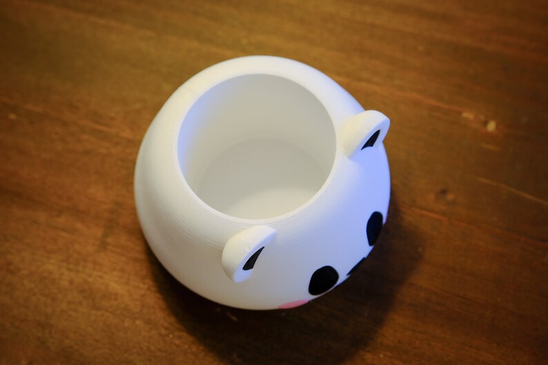 May include: White ceramic planter shaped like a bear's face with black eyes and a pink nose.