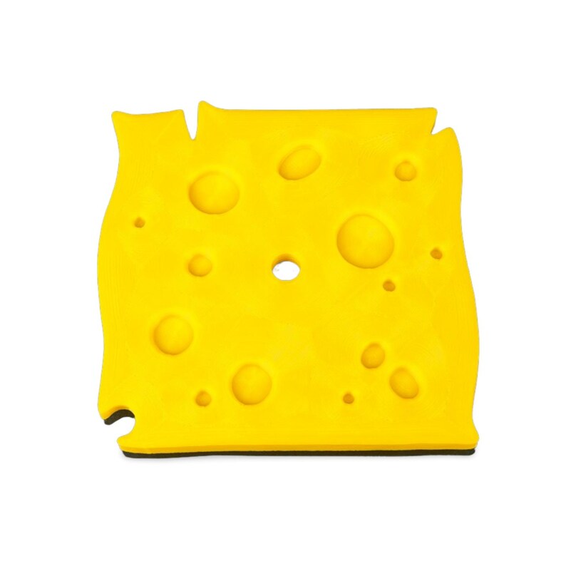 May include: A bright yellow, cheese-shaped object with multiple circular holes and a black base. The cheese has a slightly irregular shape, with a few notches along the edges, and is set against a white background.