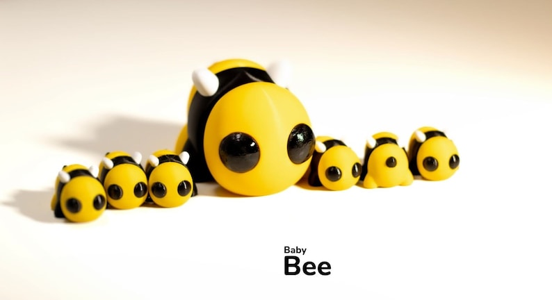 May include: A group of yellow and black bee figurines with large eyes. The largest bee is in the center and has white antennae. The text "Baby Bee" is written below the figurines.