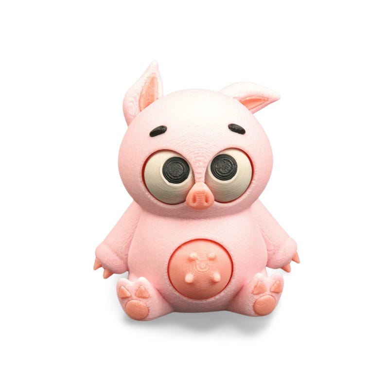 May include: A pink, cartoon-style pig figurine with large, expressive eyes and a round belly. The pig has small ears, a button-like belly detail, and is sitting with its legs crossed. The figurine is made of a textured material.