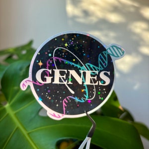 May include: A black and white sticker with a holographic finish. The sticker features a DNA strand with the word "GENES" in white letters. The background is black with a scattering of white stars.