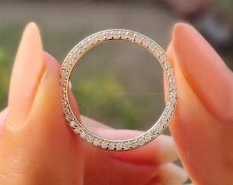 May include: A thin gold band ring with a row of small, clear diamonds encircling the band.