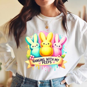 May include: White sweatshirt with a graphic of three colorful Peeps marshmallow candies and the text "Hanging with my Peeps".